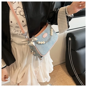 Détail du sac à bandoulière en denim bleu clair avec garniture en cuir rose et perles
