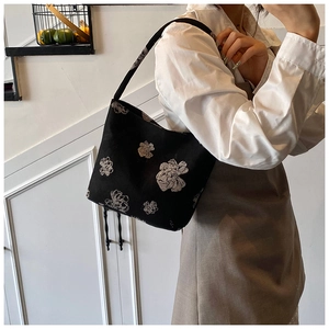 Close-up of black canvas shoulder bag with vintage white floral print on a female model
