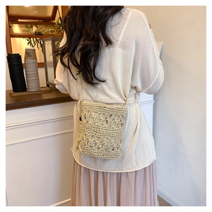 Detailed view of handmade beige woven bucket bag with floral patterns and tassel accents