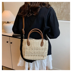 Detail showing the brown leather strap and hand-woven straw texture of the bucket bag