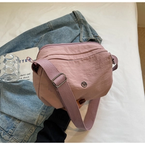 Détail du sac bandoulière en nylon rose avec compartiments zippés et logo métallique