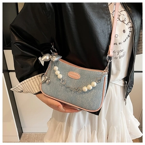 Détail d'un sac à bandoulière en jean bleu clair avec bordure en cuir rose et perles