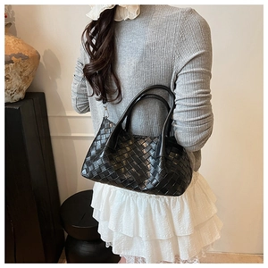 Détail d'un sac seau tissé noir avec anses rondes et design moderne et élégant