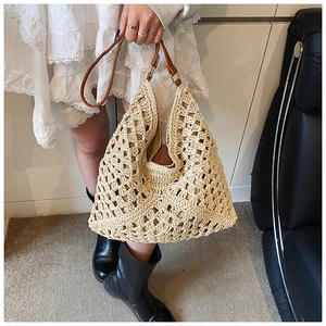 Detail of the hollow woven straw tote bag with brown leather handles for beach vacation