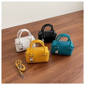 Détails de quatre mini sacs Boston colorés en cuir grainé avec pendentifs métalliques
