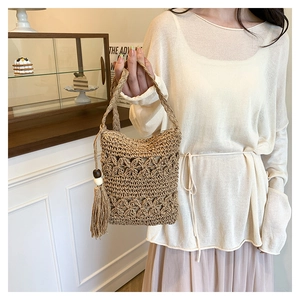 Close-up of hand-woven bucket bag with hollow pattern and large side fringe tassel