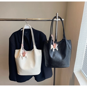 Detail of woven large tote bag with long shoulder straps and a white pegasus charm