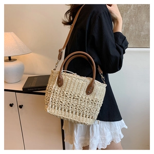 Detail of woven straw bucket bag with white drawstring liner and brown leather straps