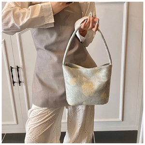 Close-up of floral jacquard bucket bag showing green fabric and matching handle