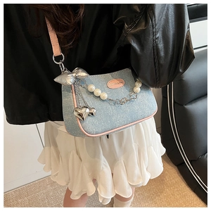 Détail du sac à bandoulière en denim bleu clair avec garniture en cuir rose et perles