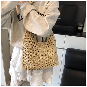 Detail of hand-woven beige straw bag with geometric hollow pattern for summer beach