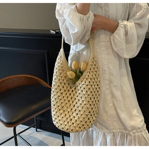 Detailed close-up showing the hollow crochet texture of the beige woven straw tote bag