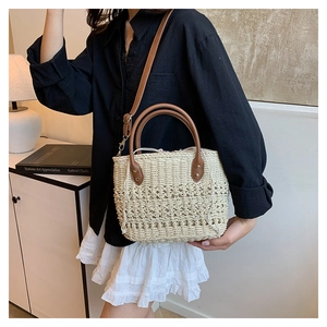 Detail of bohemian straw bucket bag with brown leather handles and drawstring lining