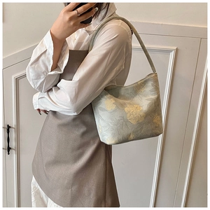 Detailed view of a green floral jacquard crescent underarm bag worn over a white shirt