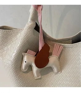 Detail of creative pegasus charm accessory attached to a woven white handbag strap