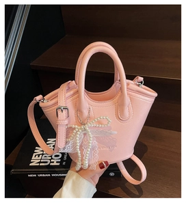 Detail of pink leather bucket bag with pearl bow, lace trim and silver hardware accents