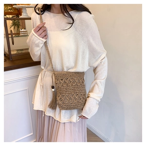 Detail of hand-woven straw bucket bag with side tassels and white wood beads decoration