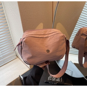 Détail du sac bandoulière rose multicouche avec sangle réglable et logo métallique