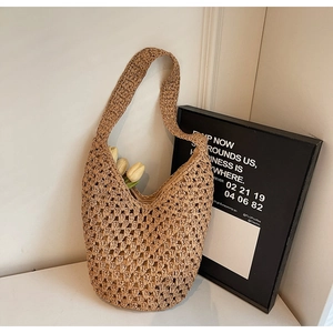 Detail of hollow woven straw shoulder bag with minimalist design and beach style texture