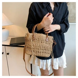 Straw bucket bag detail with brown leather strap and intricate hollow crochet texture