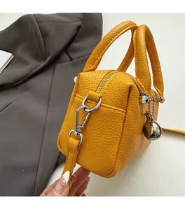 Détail d'un sac Boston en cuir jaune grainé avec fermeture éclair argentée et pendentif