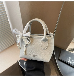 Detail of light gray lychee grain leather mini handbag with pearl and satin bow charms