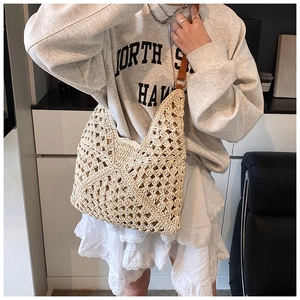 Detail of hollow geometric hand-woven straw tote bag with brown leather shoulder straps