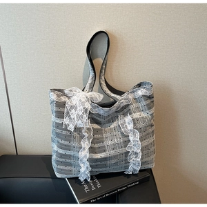 Détail du sac cabas en tulle gris avec des nœuds en dentelle blanche et anses noires