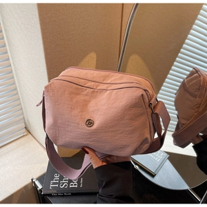 Détail du sac bandoulière en nylon rose avec plusieurs fermetures éclair et texture