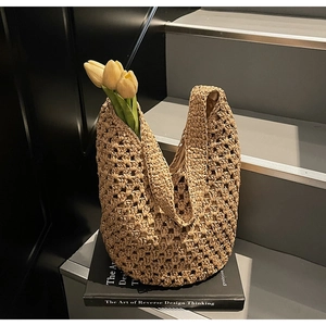 Detail of hollow woven straw tote bag with yellow tulips on a black book for summer vibes