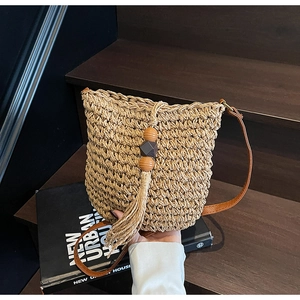 Dettaglio borsa a secchiello in paglia intrecciata con frange e perline di legno per vacanze