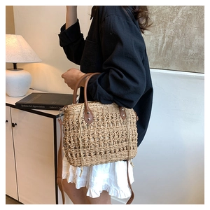 Detailed view of woven straw bucket bag with leather handles and drawstring lining