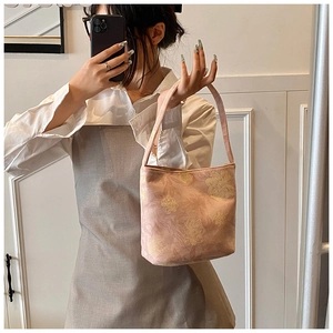 Detailed view of light pink bucket bag with yellow floral patterns and slim shoulder strap