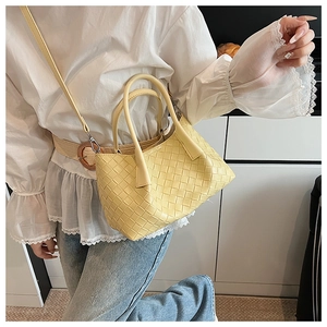 Gros plan sur le sac en cuir tressé jaune montrant la texture quadrillée et l'anse