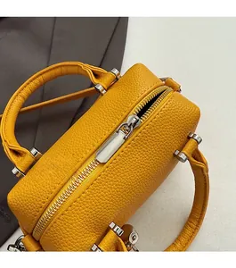 Vue détaillée du zip en métal argenté et du cuir grainé jaune sur le sac Boston