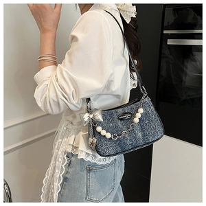 Detail view of denim underarm bag with pearl chain and silver butterfly charms