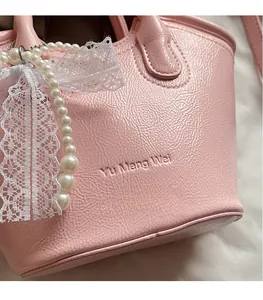 Detail of pink faux leather bucket bag with lychee texture and pearl lace bow