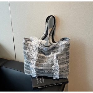 Détail du sac cabas à carreaux gris avec dentelle blanche et grand nœud sur le côté