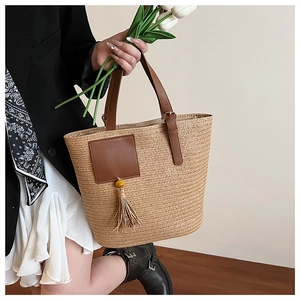 Detail of straw woven tote bag with leather pocket and decorative beaded tassel