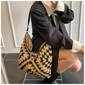 Hobo style hand-knitted shoulder tote with black and beige floral pattern on a female model