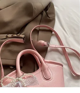 Detailed view of pink lychee leather handbag with pearl bow and lace trim details