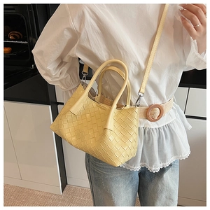 Détail d'un sac à main tissé jaune clair avec bandoulière porté par un mannequin