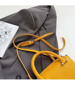 Détail de la texture cuir grainé jaune et des ferrures argentées sur le sac à main