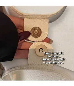 Detailed macro view of gold magnetic snap closure on white embossed leather tote bag