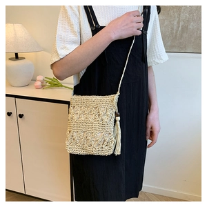 Detail of woven straw bucket bag with tassels and wooden beads on a shoulder strap