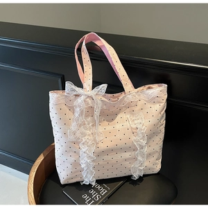 Détail du sac cabas rose à pois avec dentelle blanche et nœud sur un siège noir chic