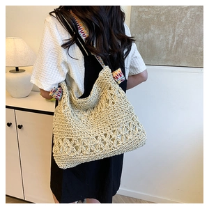 Detail of crochet straw tote with hollow floral patterns and ethnic colorful shoulder strap