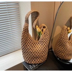 Detail of hand-woven hollow straw shoulder bag showing natural texture and mesh pattern