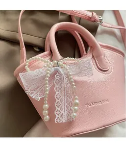 Close-up of pink leather handbag featuring pearl lace bow and Yu Meng Wei brand logo
