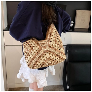 Detail of a large handmade woven straw tote bag with beige and brown geometric patterns